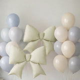 Green and blue balloons with large decorative bows on a plain background.