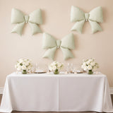 Elegant mint green bows on a wall above a beautifully set dining table with floral arrangements.
