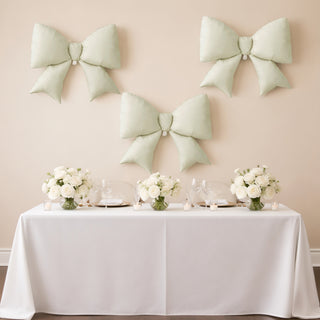 Elegant mint green bows on a wall above a beautifully set dining table with floral arrangements.