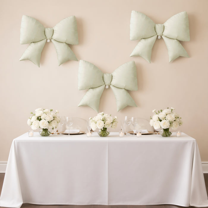 Elegant mint green bows on a wall above a beautifully set dining table with floral arrangements.