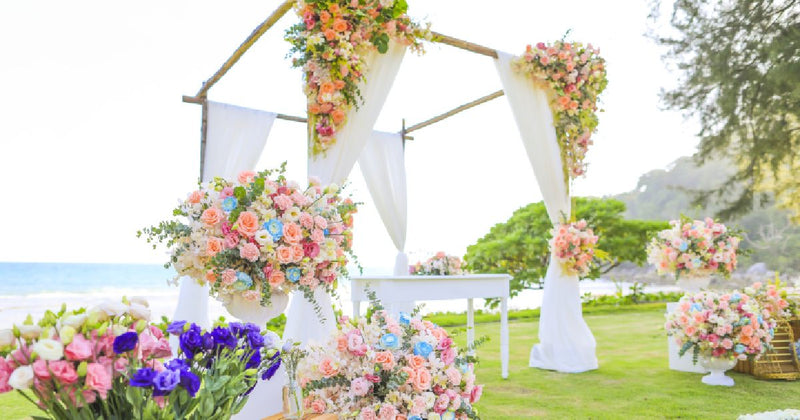 Beach wedding arch with white drapes and floral arrangements