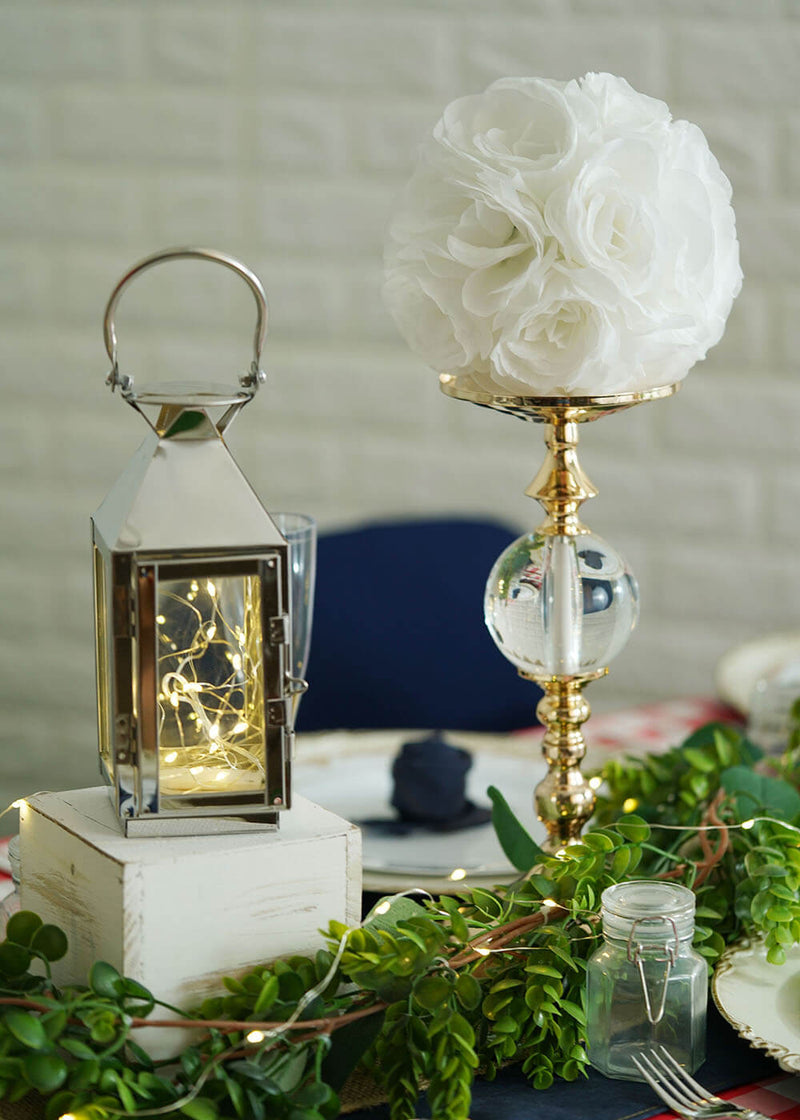 Table centerpiece with lanterns and red floral topiary