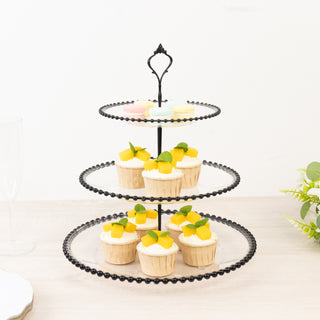 Three-tiered black dessert stand with cupcakes and mango toppings.