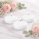 White floating candles surrounded by pink roses and greenery.
