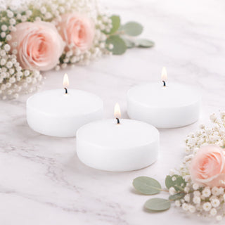 White floating candles surrounded by pink roses and greenery.