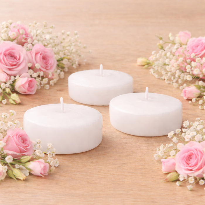 White tea light candles surrounded by pink roses and baby's breath flowers.