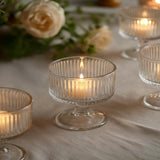 Elegant ribbed glass candle holders with lit candles on a table centerpiece