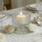 Elegant white candle centerpiece with roses and glassware on a table.