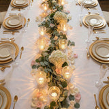 Elegant gold wedding table setting with floral eucalyptus centerpiece and candles