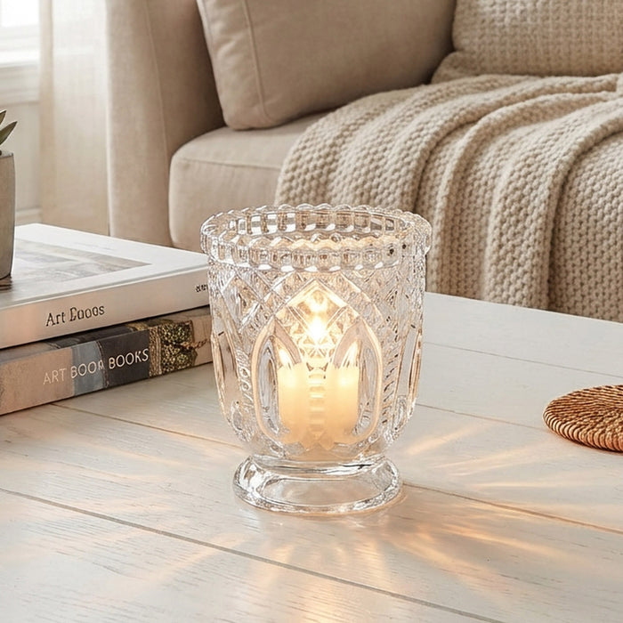 Glass candle holder with lit candle on a cozy living room coffee table