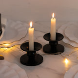 Black candle holders with lit candles on a marble surface.