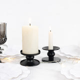 Black candle holders with white candles on a table setting.