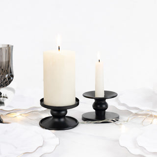 Black candle holders with white candles on a table setting.