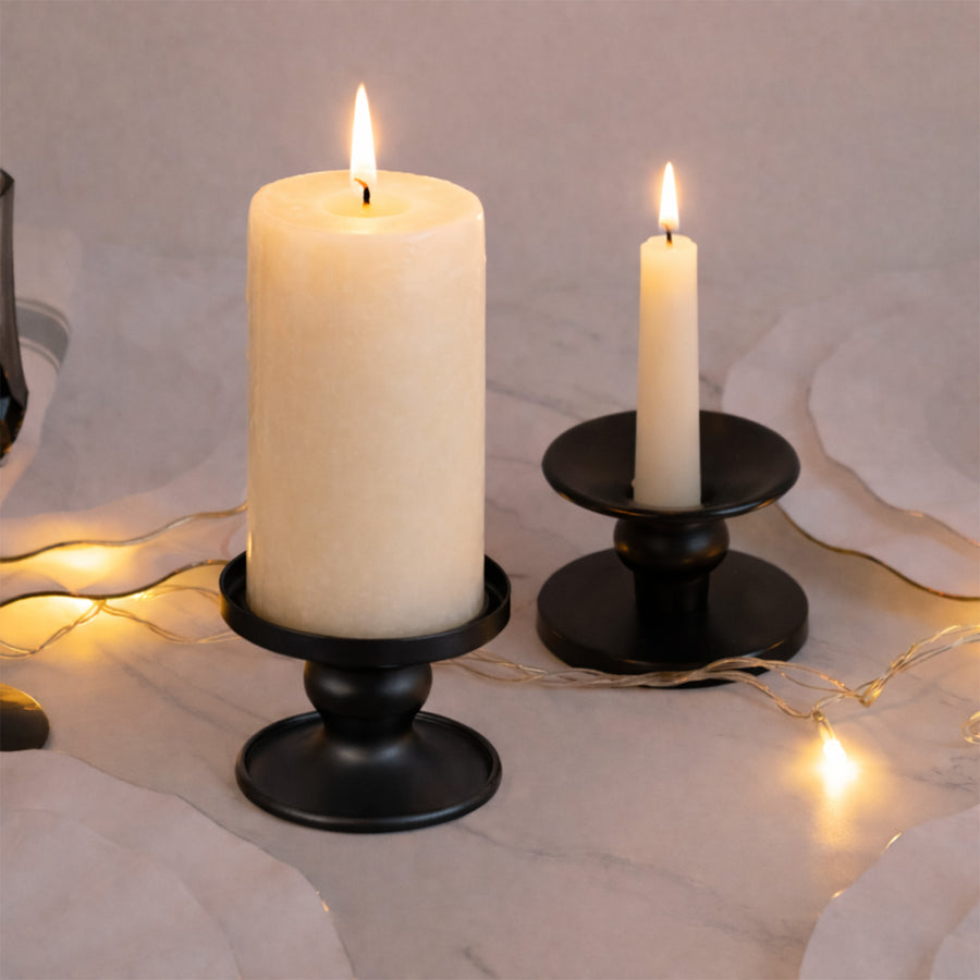 Black candle holders with ivory candles lit, surrounded by warm fairy lights.