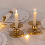 Gold candle holders with white candles and fairy lights on a marble table.