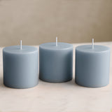 Three blue pillar candles on a marble surface.