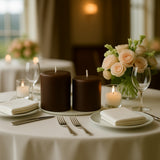Elegant brown candles on a dining table with floral centerpiece and dinnerware.