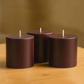 Brown cylindrical candles grouped on a wooden surface.