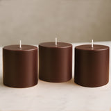 Brown cylindrical candles in varying heights on a marble surface.
