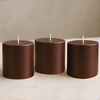 Brown cylindrical candles in varying heights on a marble surface.