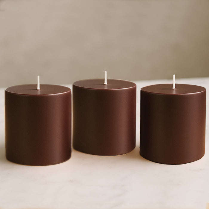 Brown cylindrical candles in varying heights on a marble surface.