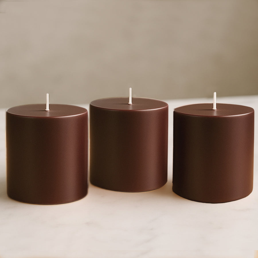 Brown cylindrical candles in varying heights on a marble surface.