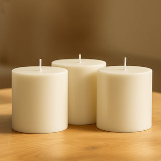 Three ivory pillar candles on a wooden table.