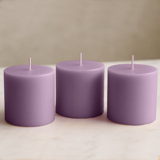 Purple pillar candles set on a marble surface.