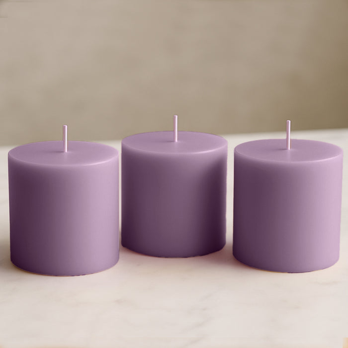 Purple pillar candles set on a marble surface.