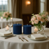 Blue candles on a elegantly set dining table with roses and glassware.