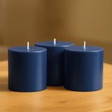 Set of three navy blue candles on a wooden table.