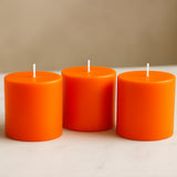 Three vibrant orange candles arranged in a row.
