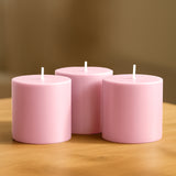 Pink decorative candles in varying heights on a wooden surface.