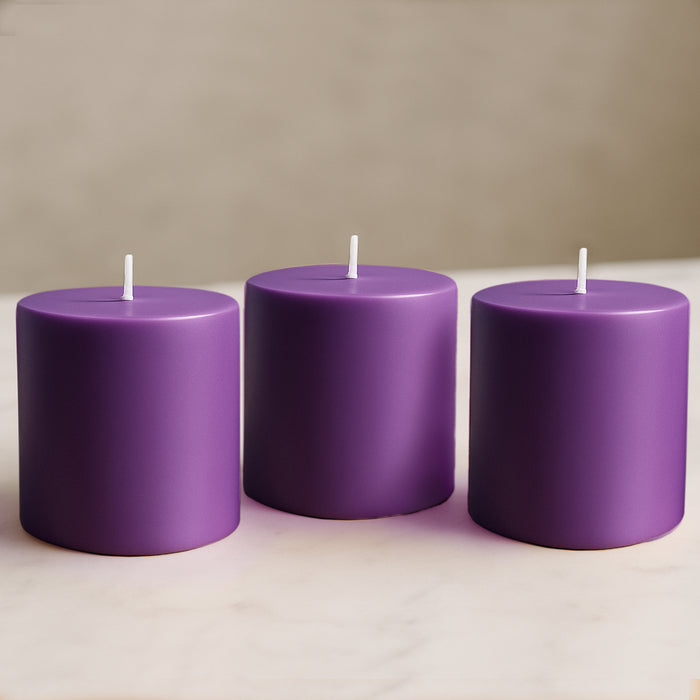 Purple pillar candles in varying heights on a marble surface.