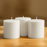 White pillar candles on a wooden table.