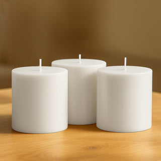 White pillar candles on a wooden table.