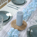 Light blue candle on a woven holder, surrounded by elegant table settings.