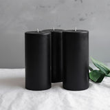 Black pillar candles grouped together on a neutral background.