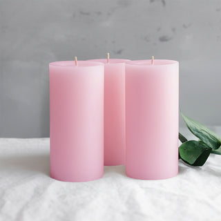 Three pink cylindrical candles with a soft matte finish.