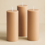 Set of three beige pillar candles in varying heights.