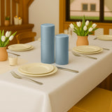 Blue decorative candles on a dining table set with plates and tulip arrangements.