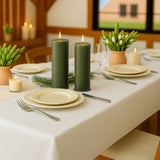 Elegant table setting with green candles, plates, and decorative plants.