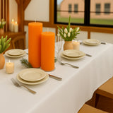 Elegant dining table setup with orange candles and tulip centerpieces.