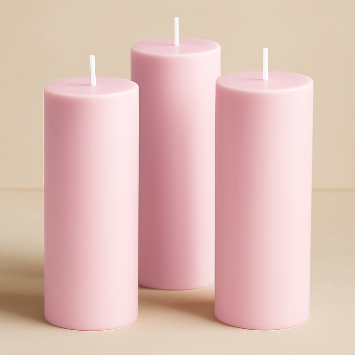Pink cylindrical candles in varying heights against a neutral background.