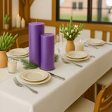 Purple candles with decorative greenery on a dining table setting.