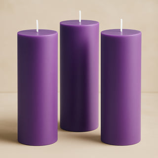 Purple pillar candles in varying heights on a neutral background.