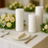 Elegant white candles with floral arrangement on a dining table setting.