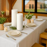 Elegant dining table set with white candles and minimalist decor.