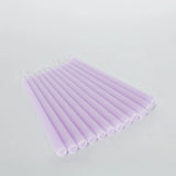 Set of 12 lavender taper candles in a studio-style isolation shot.