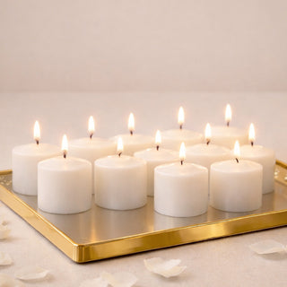 Set of 12 white candles on a gold tray with lit wicks.